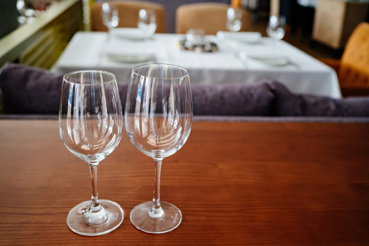 Two empty wine glasses sit on a wooden table, ready for tasting during North Fork wine tours.