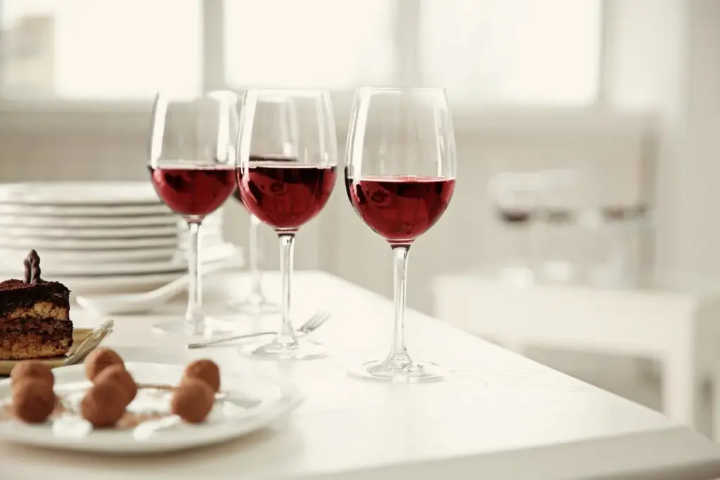 A white table set with red wine and an assortment of chocolate desserts, highlighting a delightful wine tour experience.