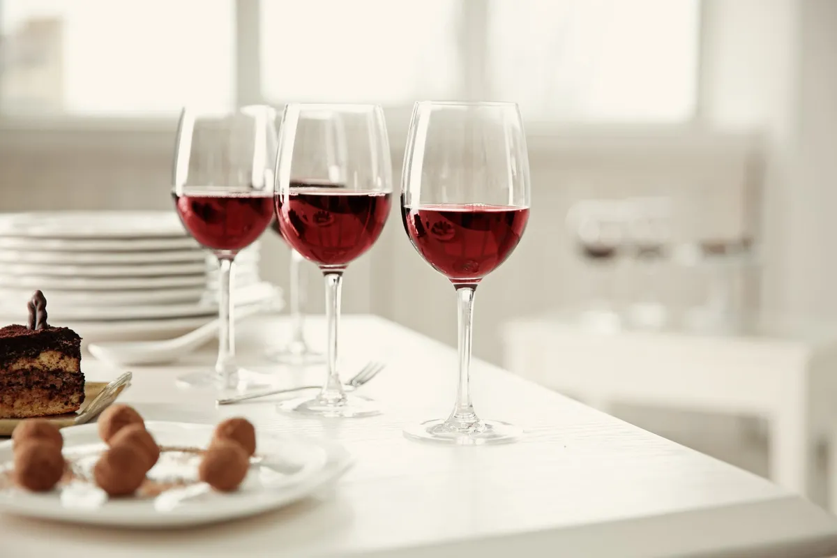 A white table set with red wine and an assortment of chocolate desserts, highlighting a delightful wine tour experience.